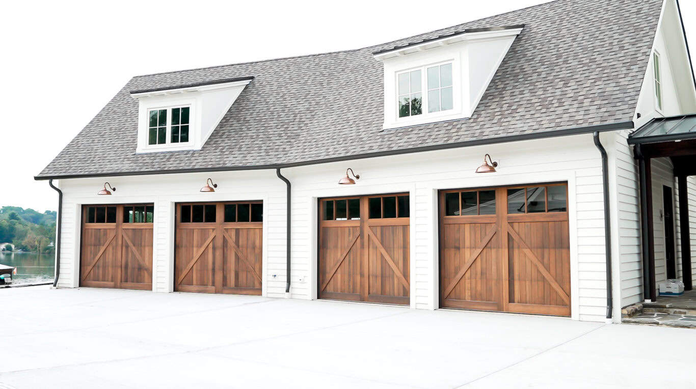 A four-car garage with wooden doors and a pitched roof, featuring two dormer windows.